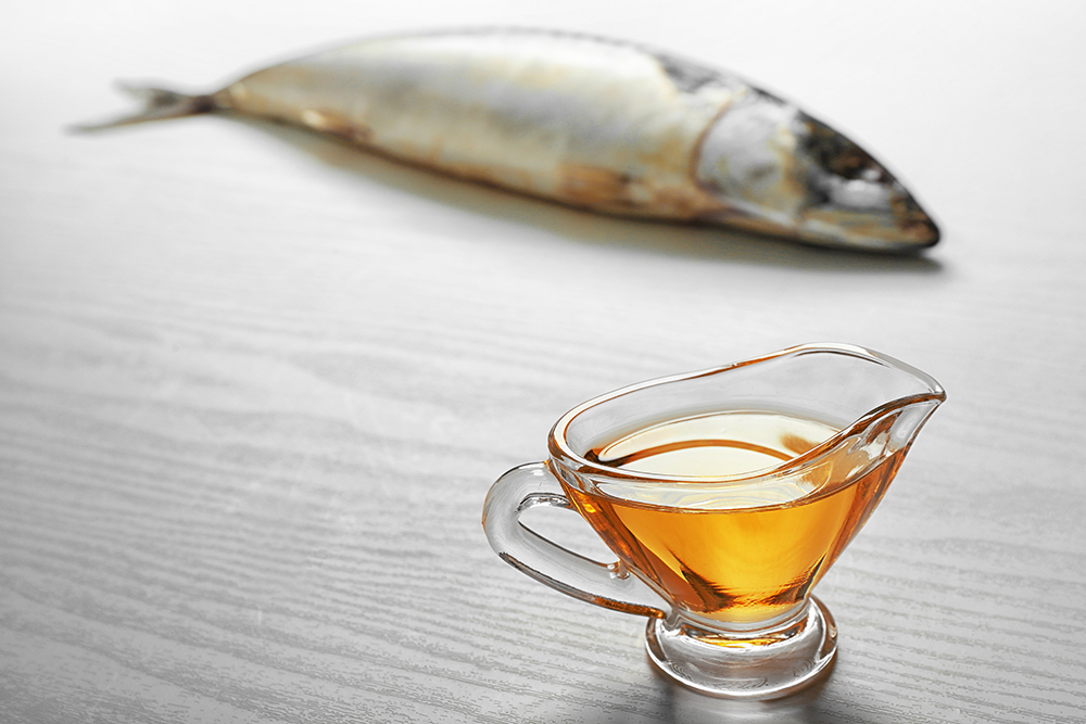 Fish oil and fresh fish on light background